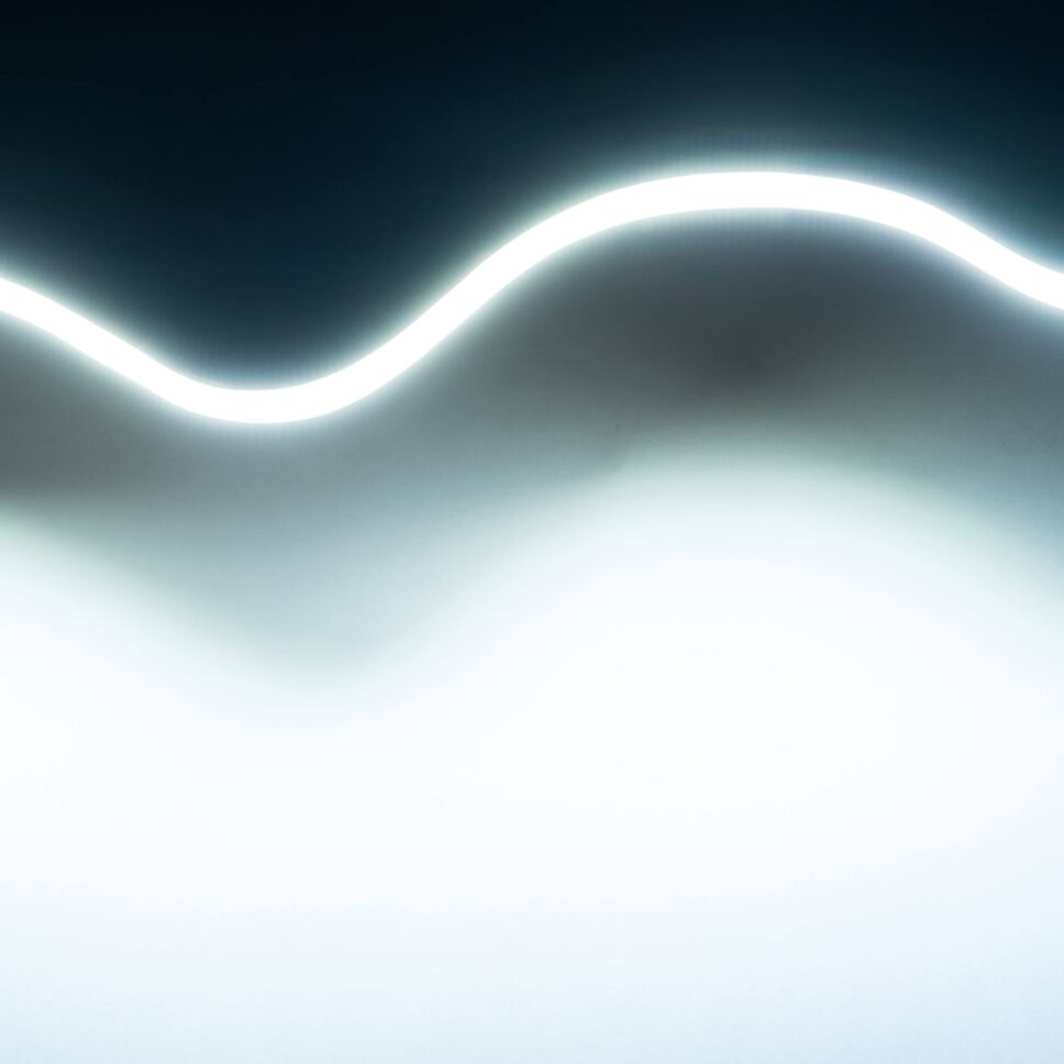 Foto vom COB LED Streifen, warmweiß leuchtend und verdreht, gehalten von 2 Händen zur Illustration der Flexibilität